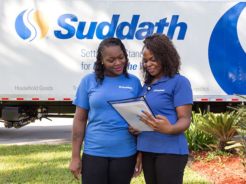 female moving team standing in front of suddath moving truck